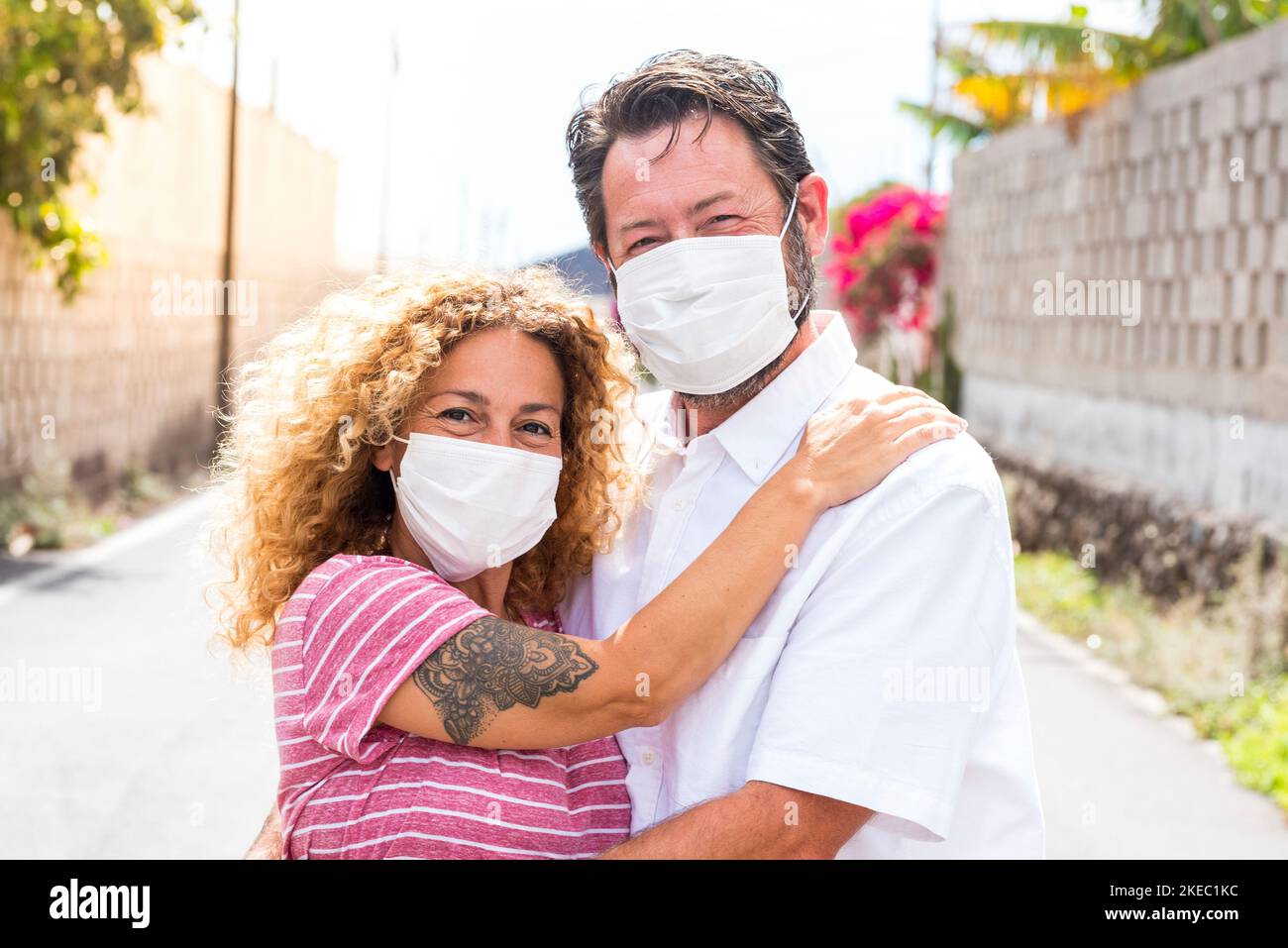 couple de gens heureux dans l'amour souriant et regardant l'appareil photo portant un masque médical et chirurgical sur le visage pour prévenir le covid-19 ou tout type de maladie ou de grippe Banque D'Images