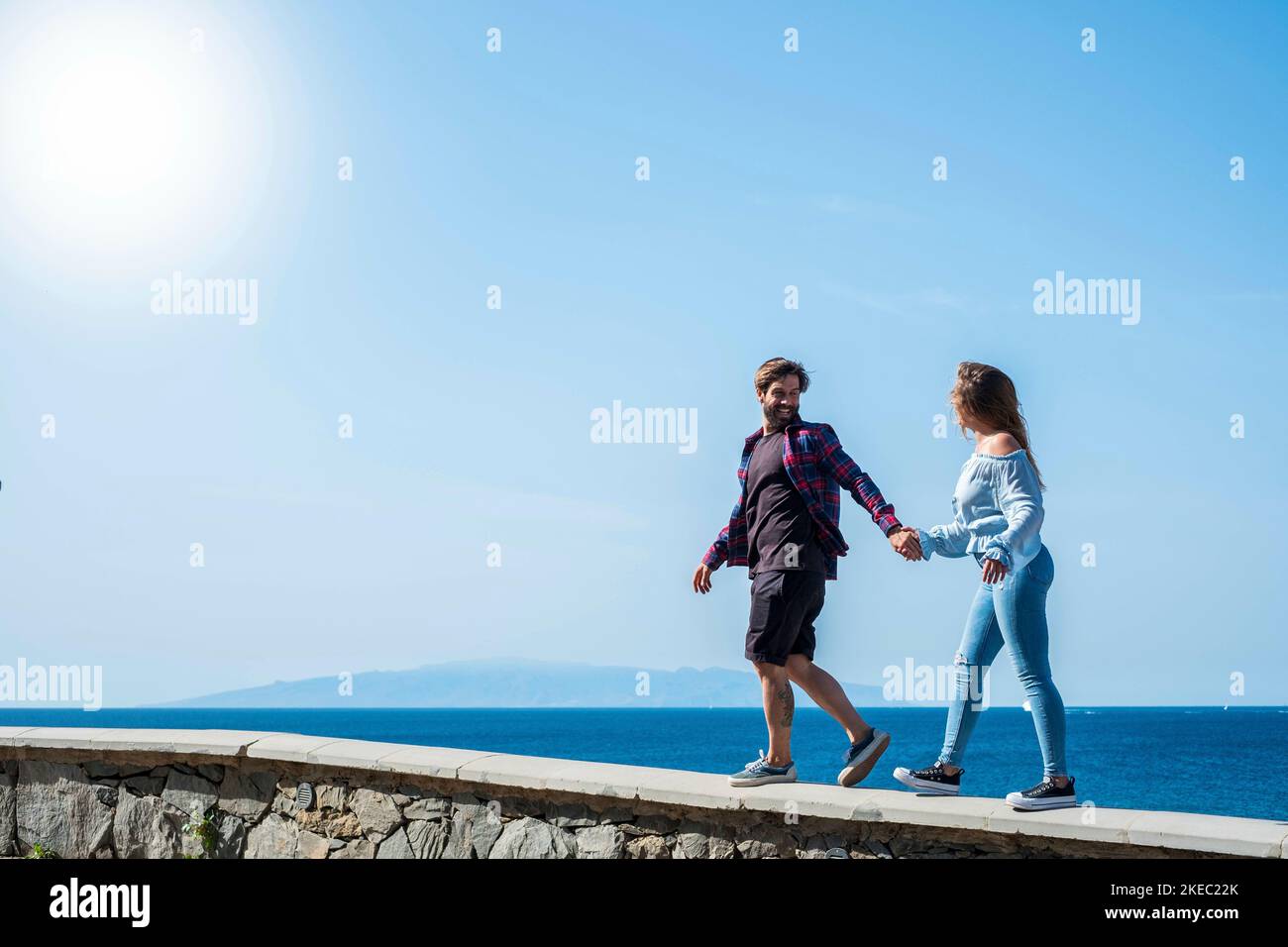 couple d'adultes marchant ensemble en prenant leurs mains avec le océan ou mer et magnifique arrière-plan de l'île - vacances heureuses togétreté - homme riant et regardant ses filles ou ami Banque D'Images