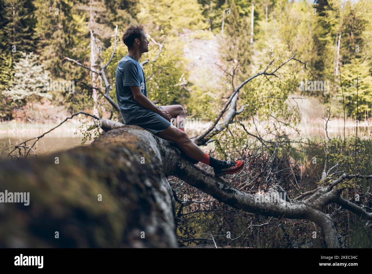 Un homme sportif fait une pause sur un tronc d'arbre Banque D'Images
