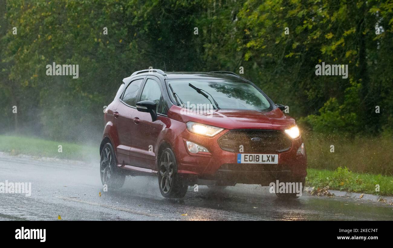 2018 rouge Ford EcoSport conduite sous la pluie sur route mouillée avec phares allumés Banque D'Images
