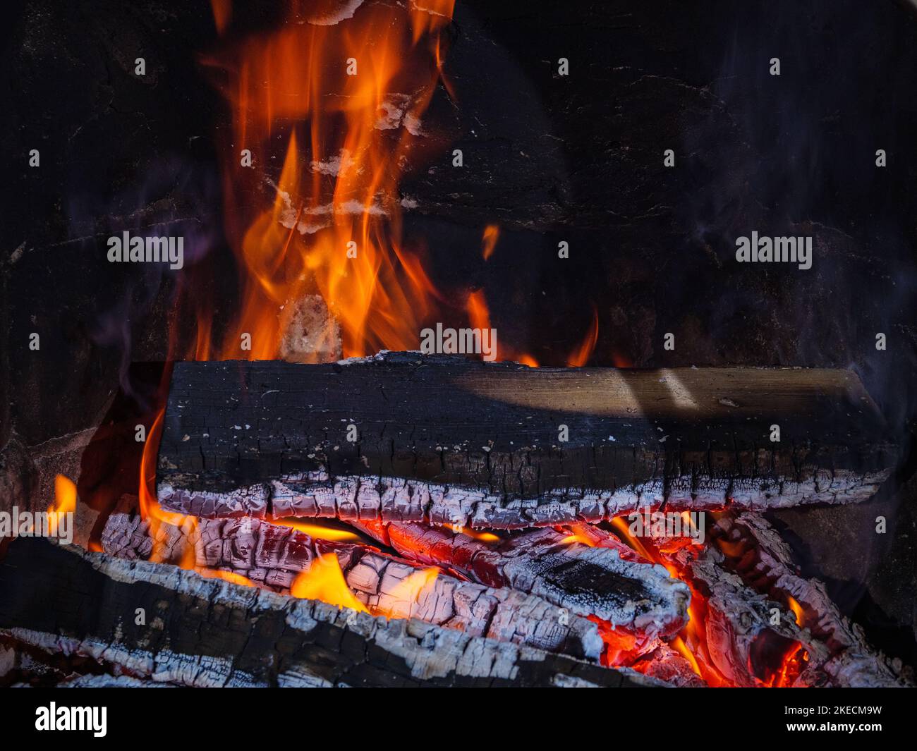 Feu de bois dans la cheminée avec des émbres et des langues de flamme Banque D'Images