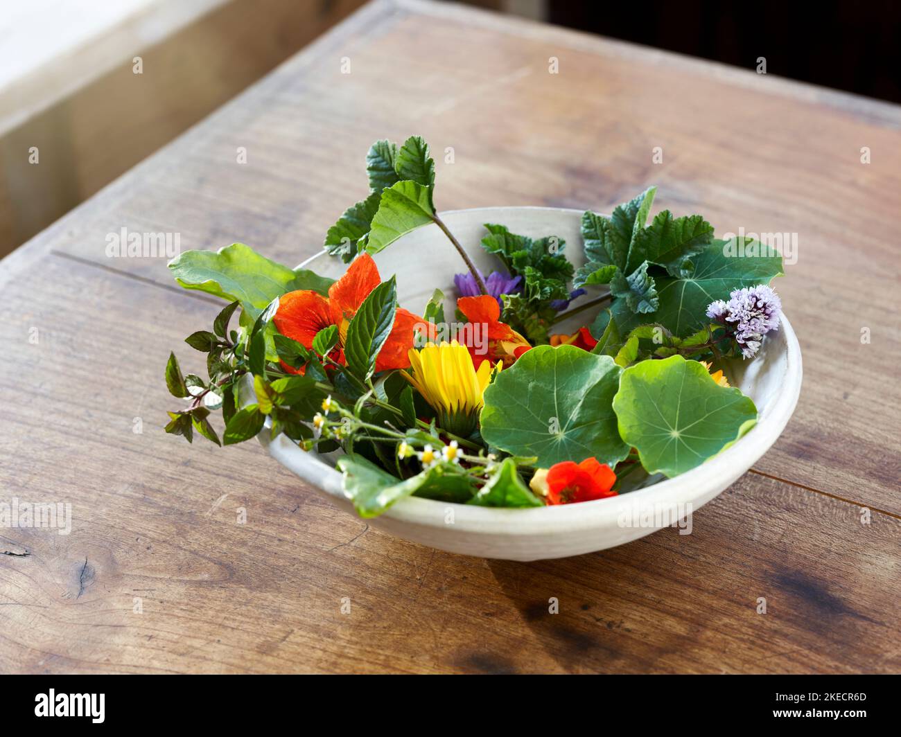 Bol avec fleurs comestibles et herbes sur une table en bois Banque D'Images