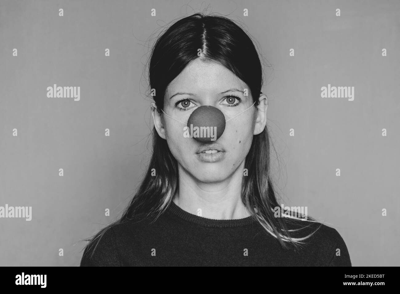 Jeune fille avec nez clown sur fond isolé photo noir et blanc Banque D'Images