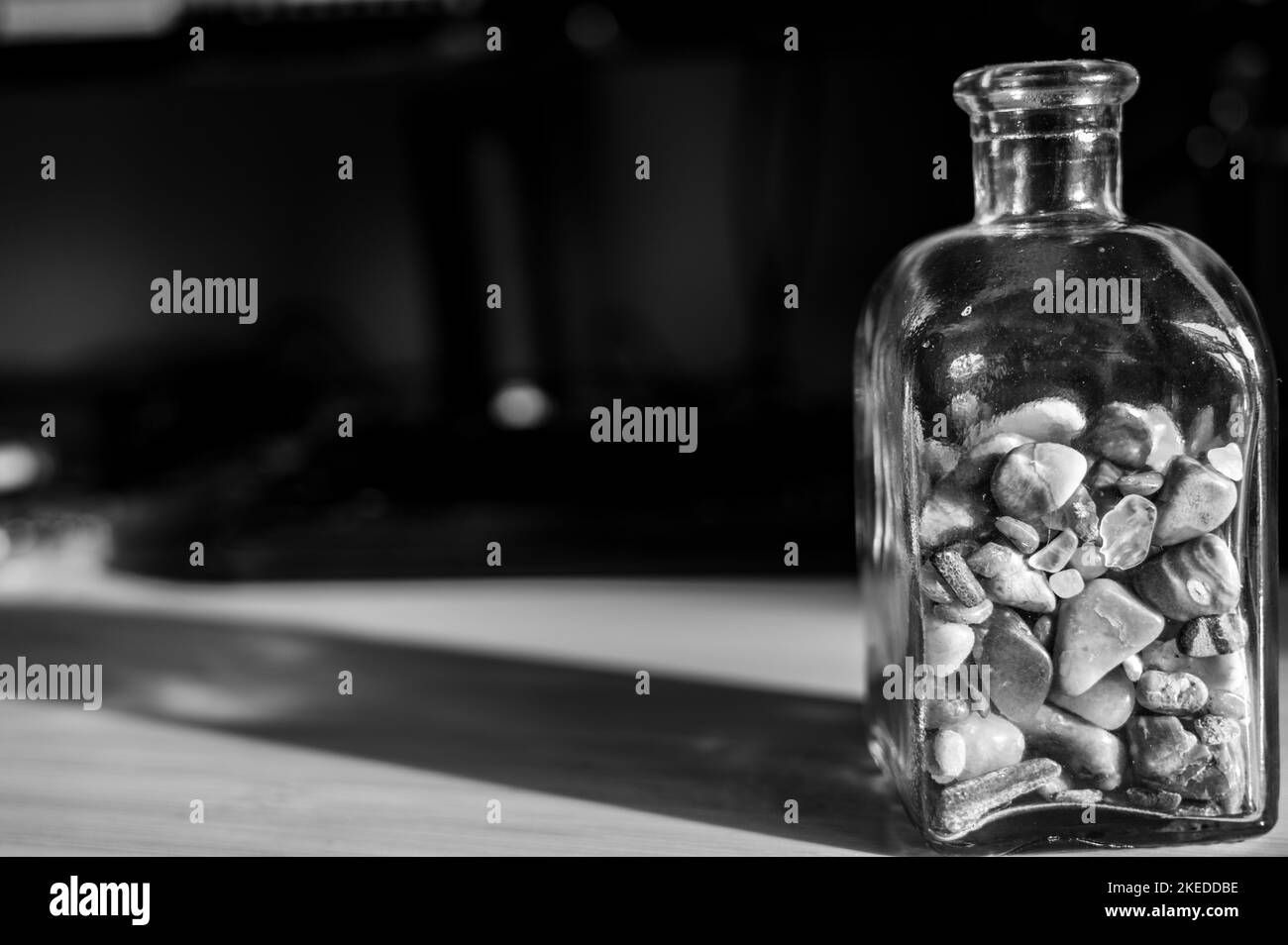 Bouteille en verre à moitié pleine de cailloux et de rochers arrondis Banque D'Images