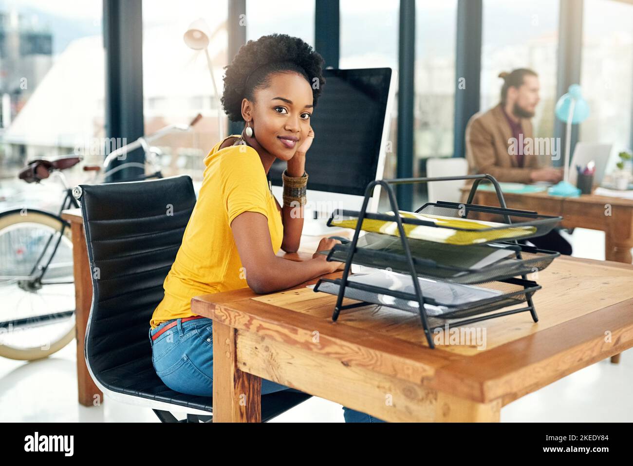 Si le succès venait à se faire facilement, personne ne le souhaiterait. Portrait d'une jeune femme d'affaires assise dans un bureau avec des collègues en arrière-plan. Banque D'Images