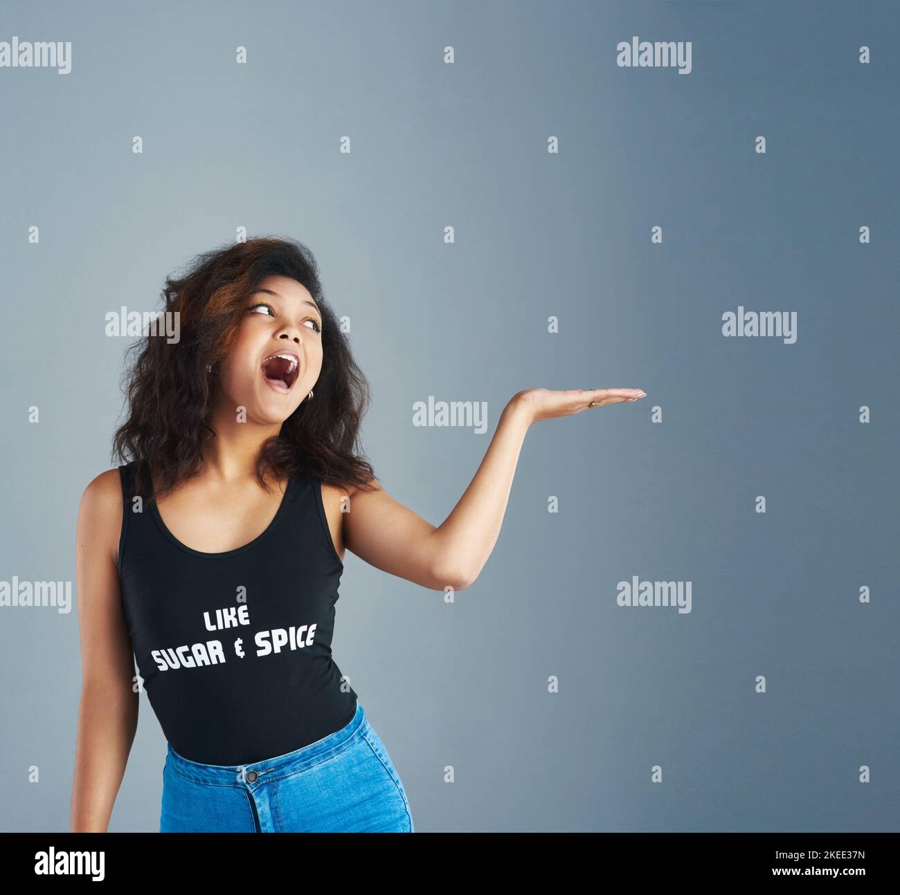Jetez un coup d'œil à cette jeune femme attirante qui se pose sur un fond gris. Banque D'Images