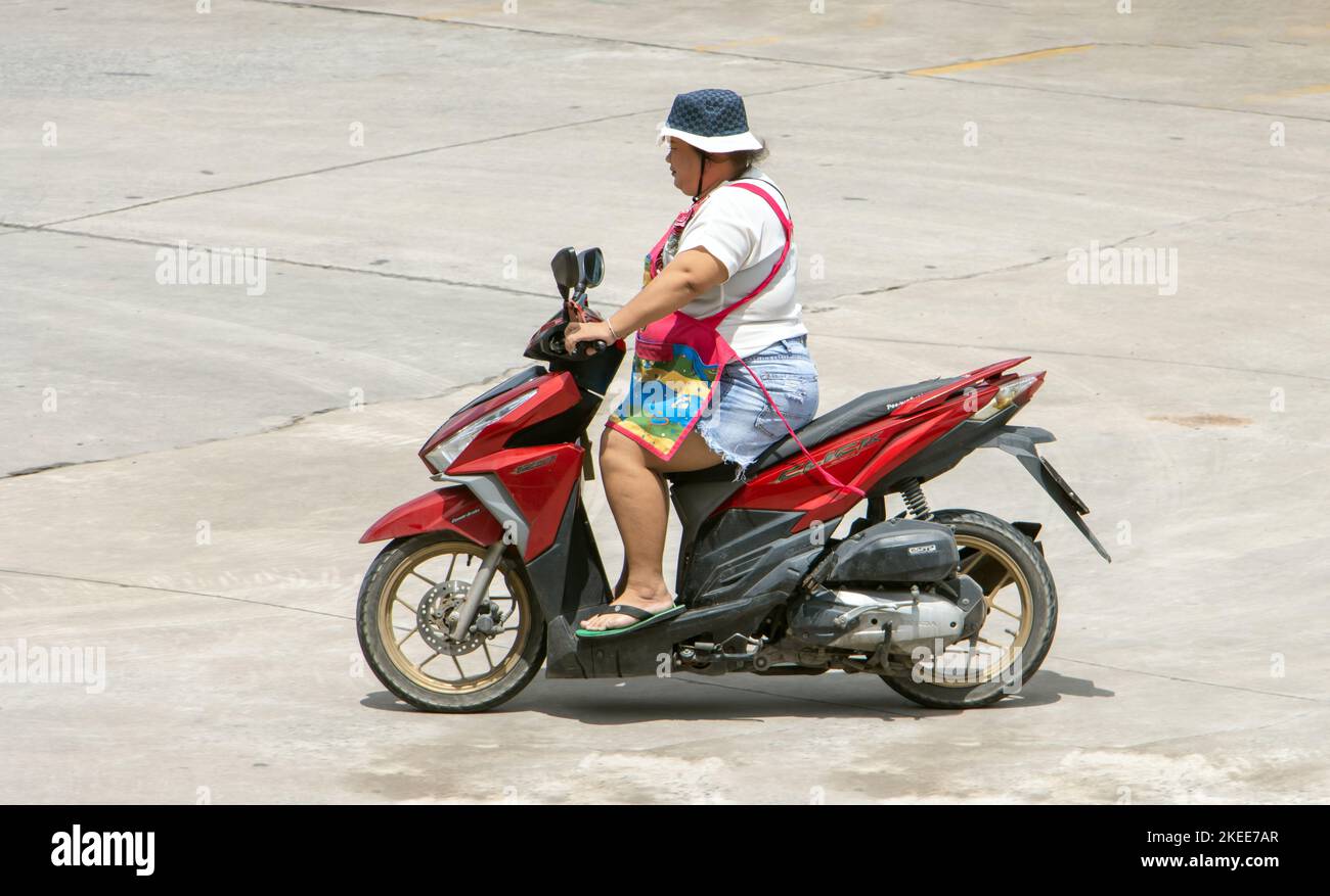 SAMUT PRAKAN, THAÏLANDE, OCT 04 2022, Une femme avec un tablier conduit une moto Banque D'Images