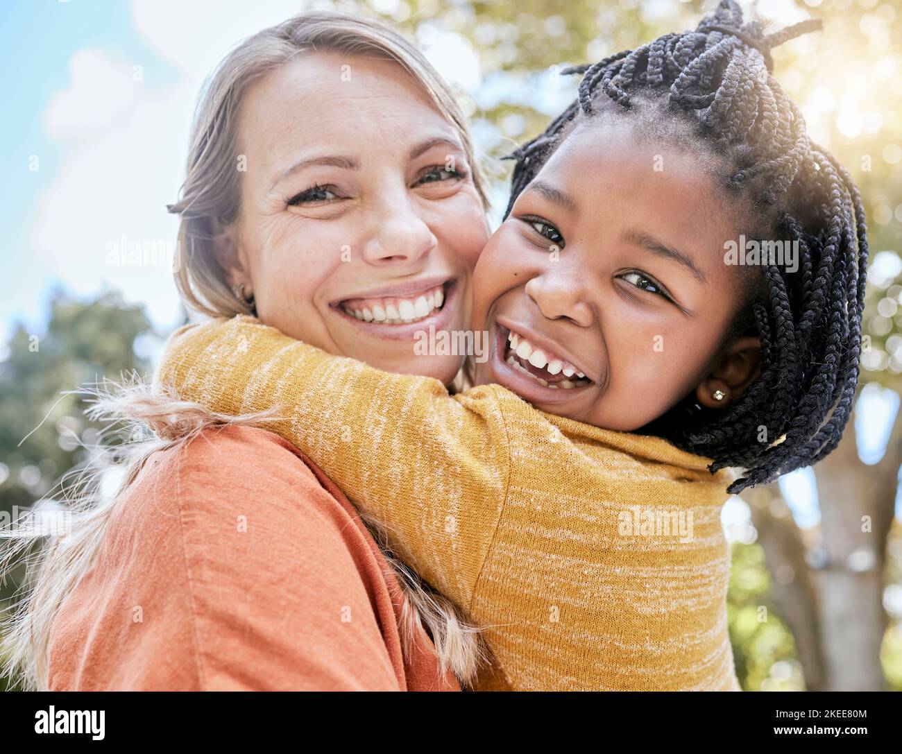Maman, enfant et interracial embrassent dans le parc avec le sourire, les arbres et le soleil en été ensemble pour le collage. Mère, enfant noir heureux et espace extérieur Banque D'Images