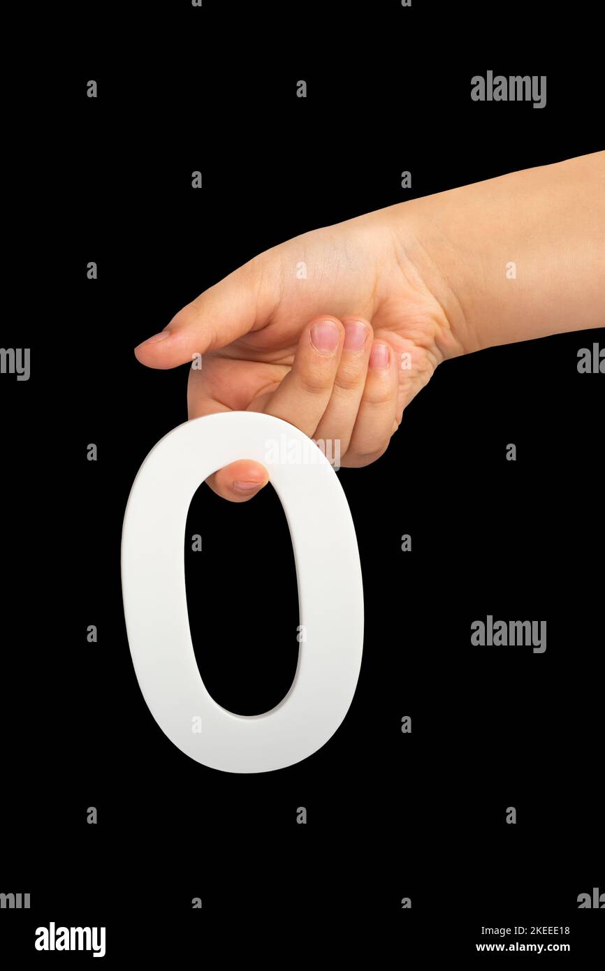 Mise à zéro en main. Le nombre zéro est cloné dans une main isolée sur un fond noir. Le blanc zéro dans la main d'un enfant sur fond noir. Banque D'Images