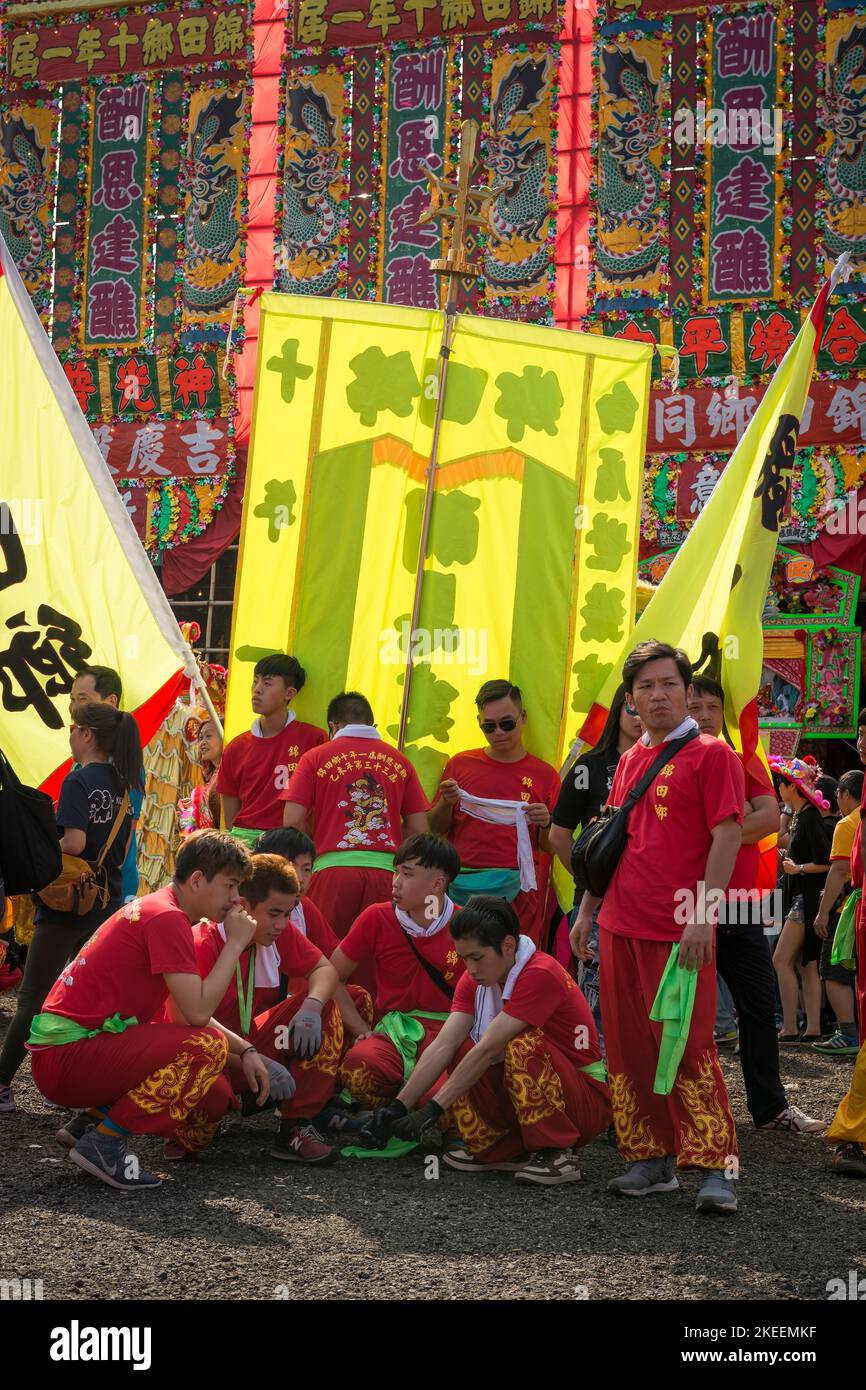 Les membres de l'équipe de danse du dragon attendent leur représentation devant les bannières cérémonielles au site du festival décennal Da JIU, Kam Tin, Hong Kong, 2015 Banque D'Images