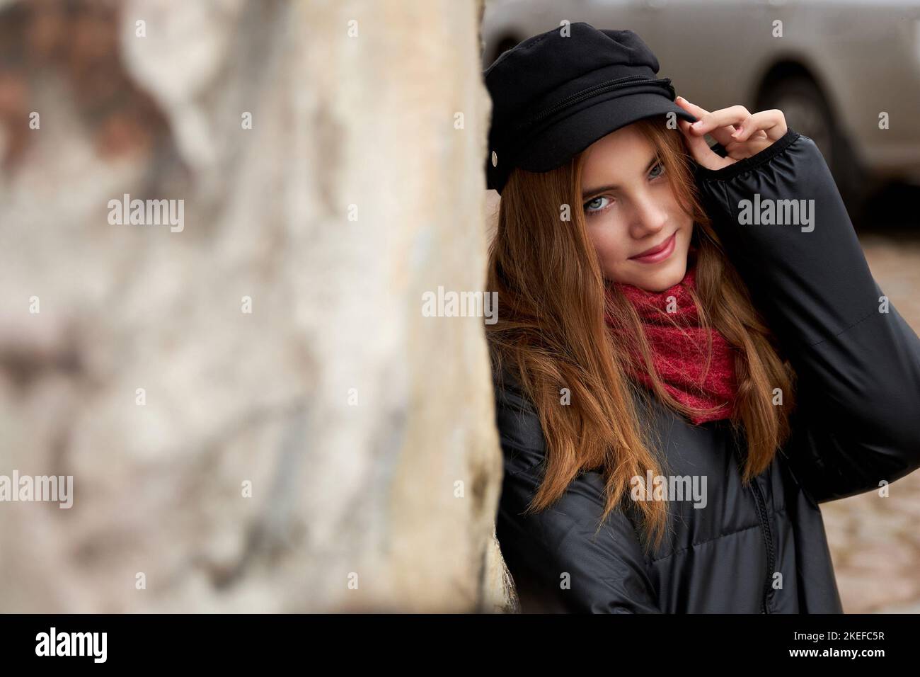 Fille dans une casquette noire avec un foulard rouge sur une rue de ville. Photo de haute qualité Banque D'Images