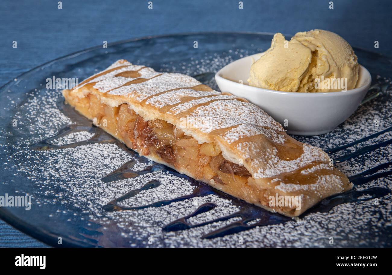 Strudel et glace à la vanille sur l'assiette et sucre en poudre. Strudel aux pommes - Apfelstrudel - Strudel di Mele Banque D'Images