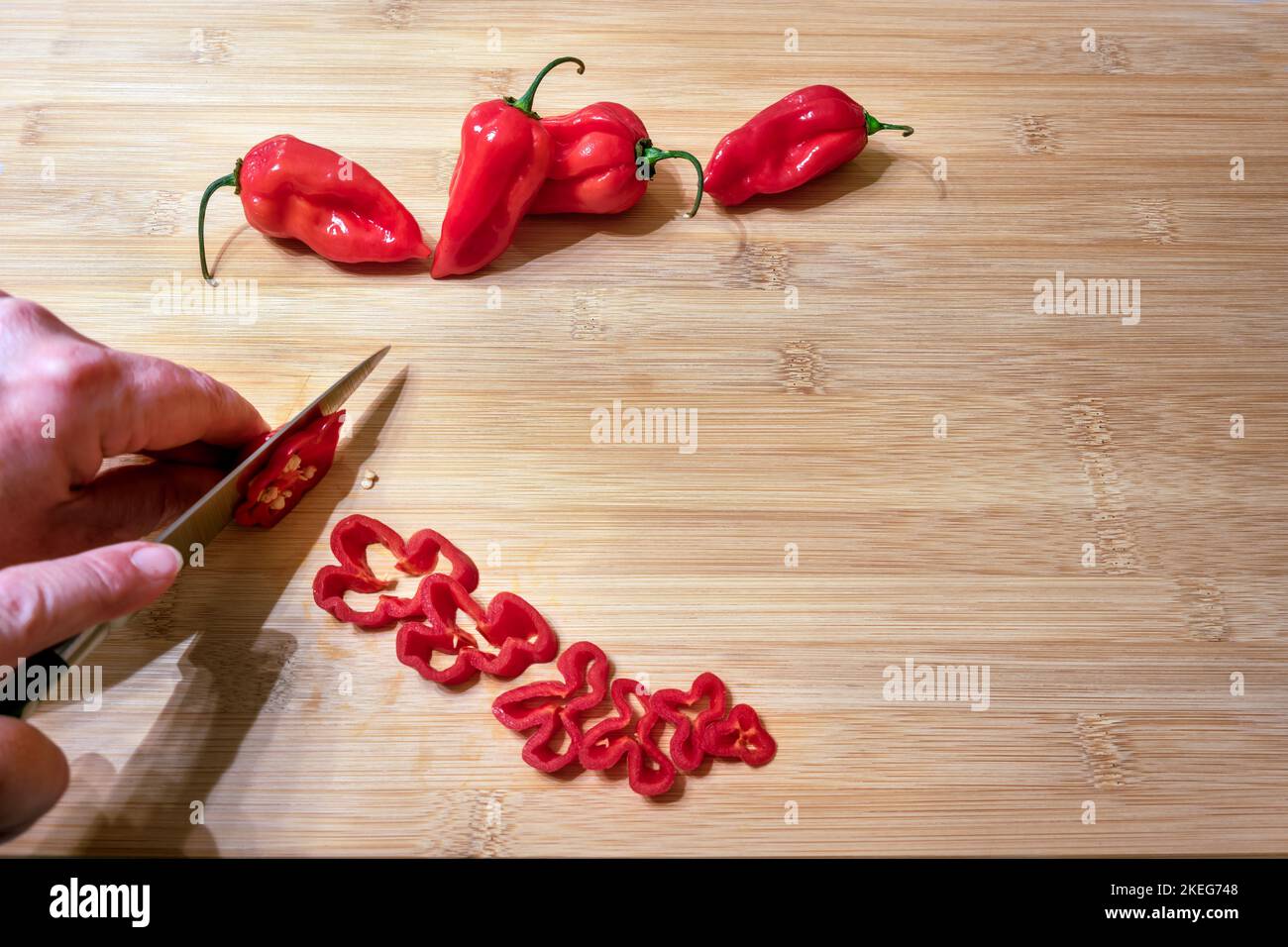 Capsicum chinense 'Scotch Bonnet' étant tranché sur une table en bois Banque D'Images