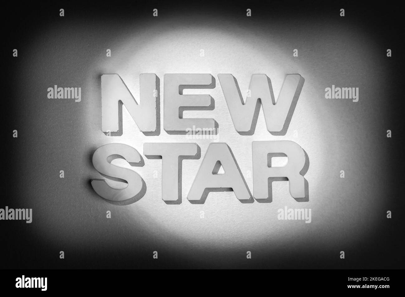 Nouvelle étoile - texte en lettres blanches dans un spot lumineux. Image de style vintage en noir et blanc Banque D'Images