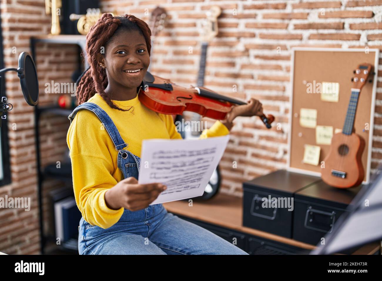 Femme africaine américaine musicienne jouant du violon regardant une feuille de musique dans un studio de musique Banque D'Images