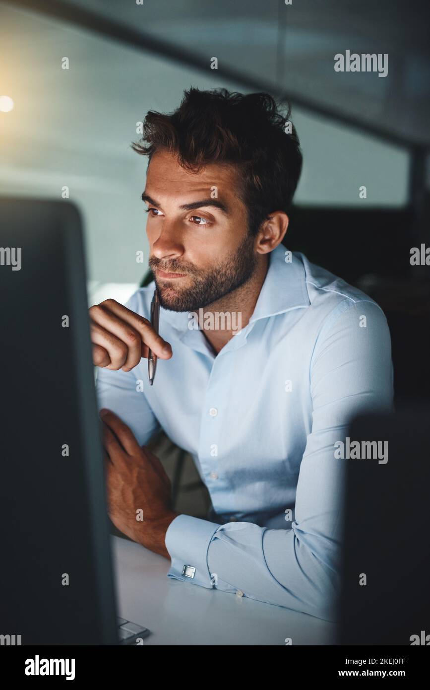 Vous avez dû faire un effort pour voir les résultats : un jeune homme d'affaires travaillant tard sur un ordinateur dans un bureau. Banque D'Images