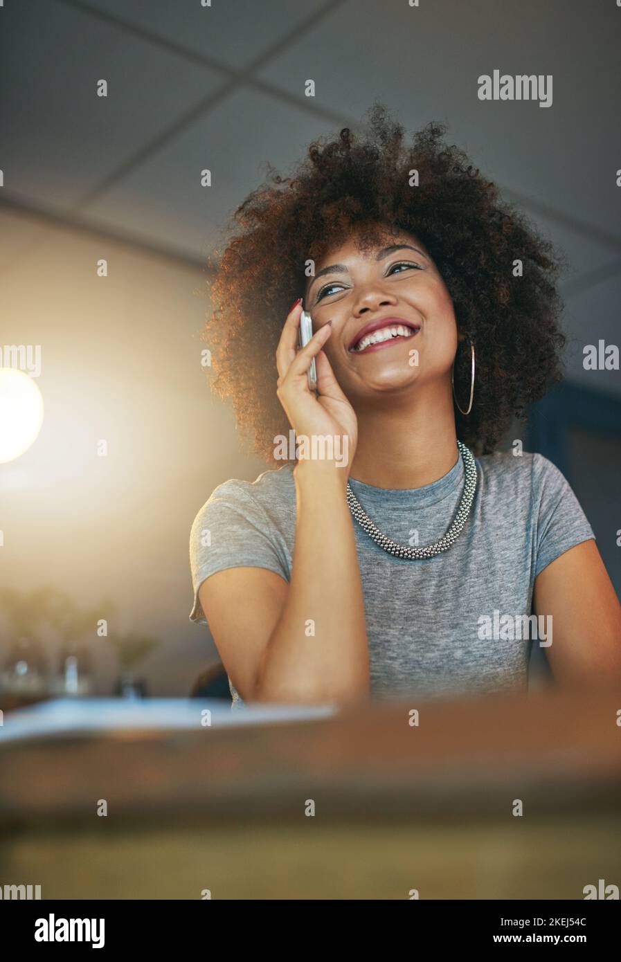 Travailler tard et aimer. Une jeune femme parlant au téléphone pendant un quart de travail tardif au bureau. Banque D'Images