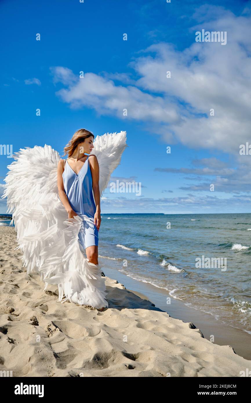 Une jeune belle femme ange avec des ailes blanches sur la plage de mer Banque D'Images