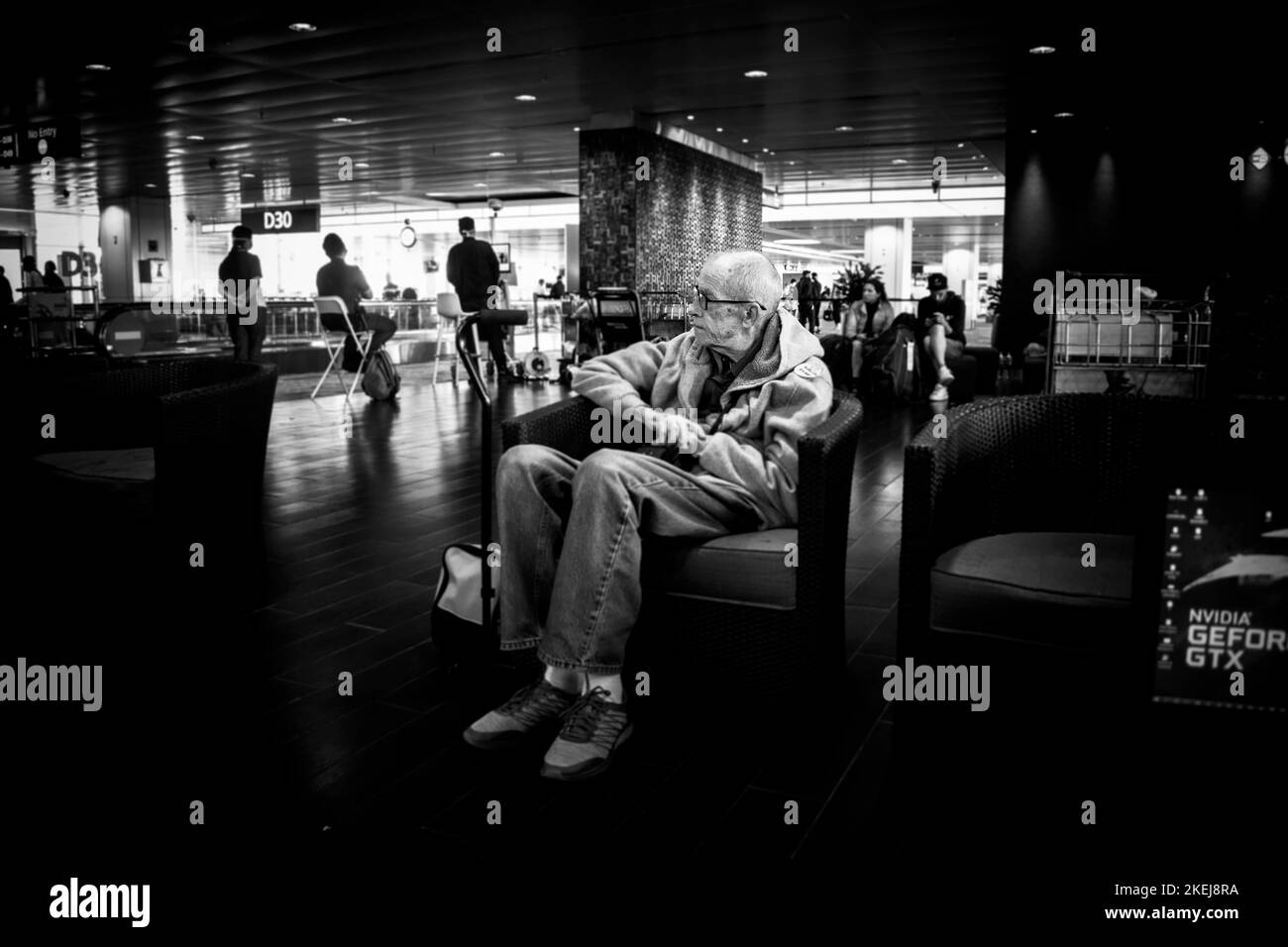 Un noir et blanc d'un vieil homme assis sur un canapé à l'aéroport de Kuala Lumpur, en Malaisie. Banque D'Images