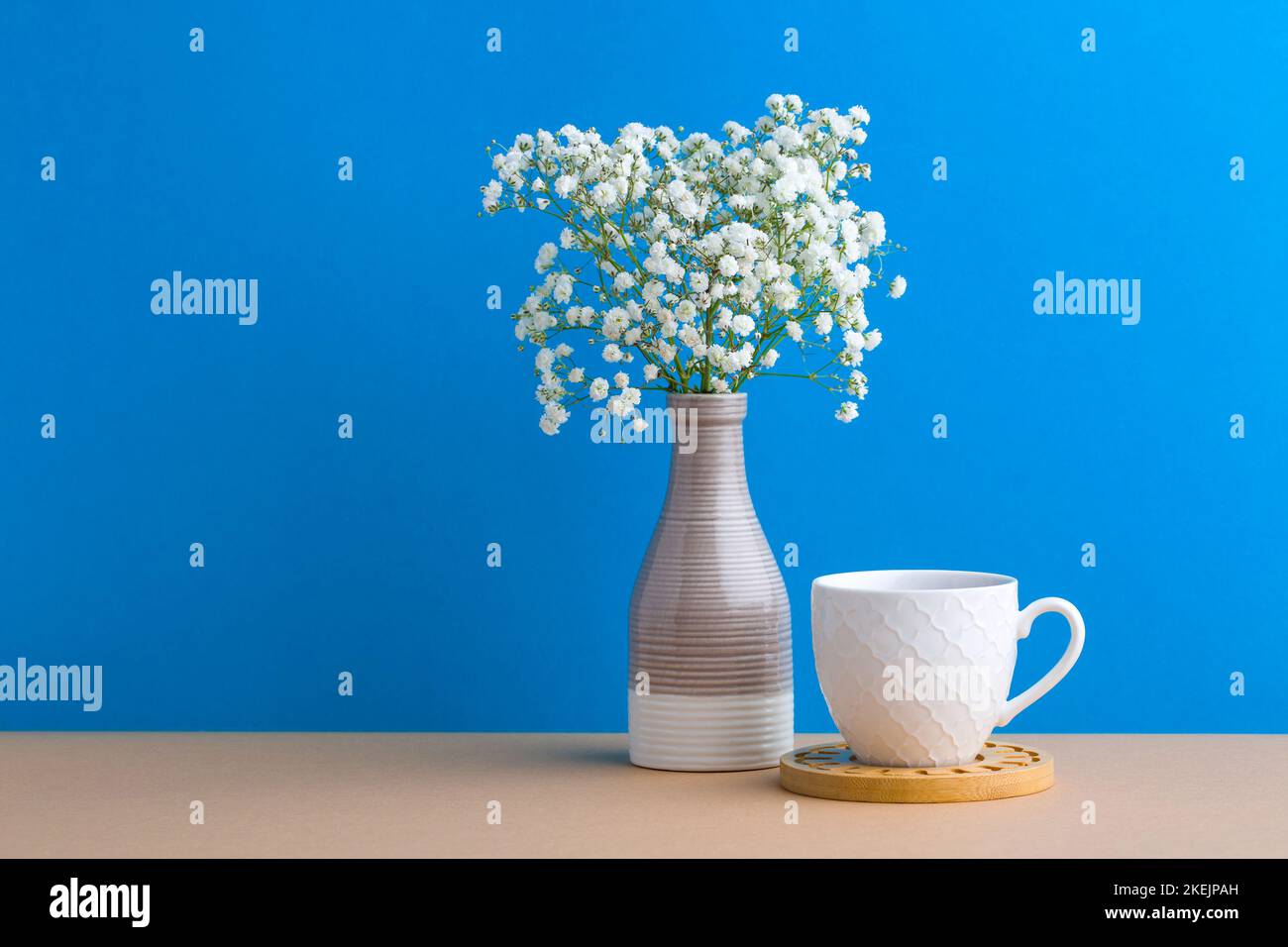 Belles petites fleurs blanches dans un vase moderne sur fond de table en bois avec espace de copie, doux tons encore vie Banque D'Images