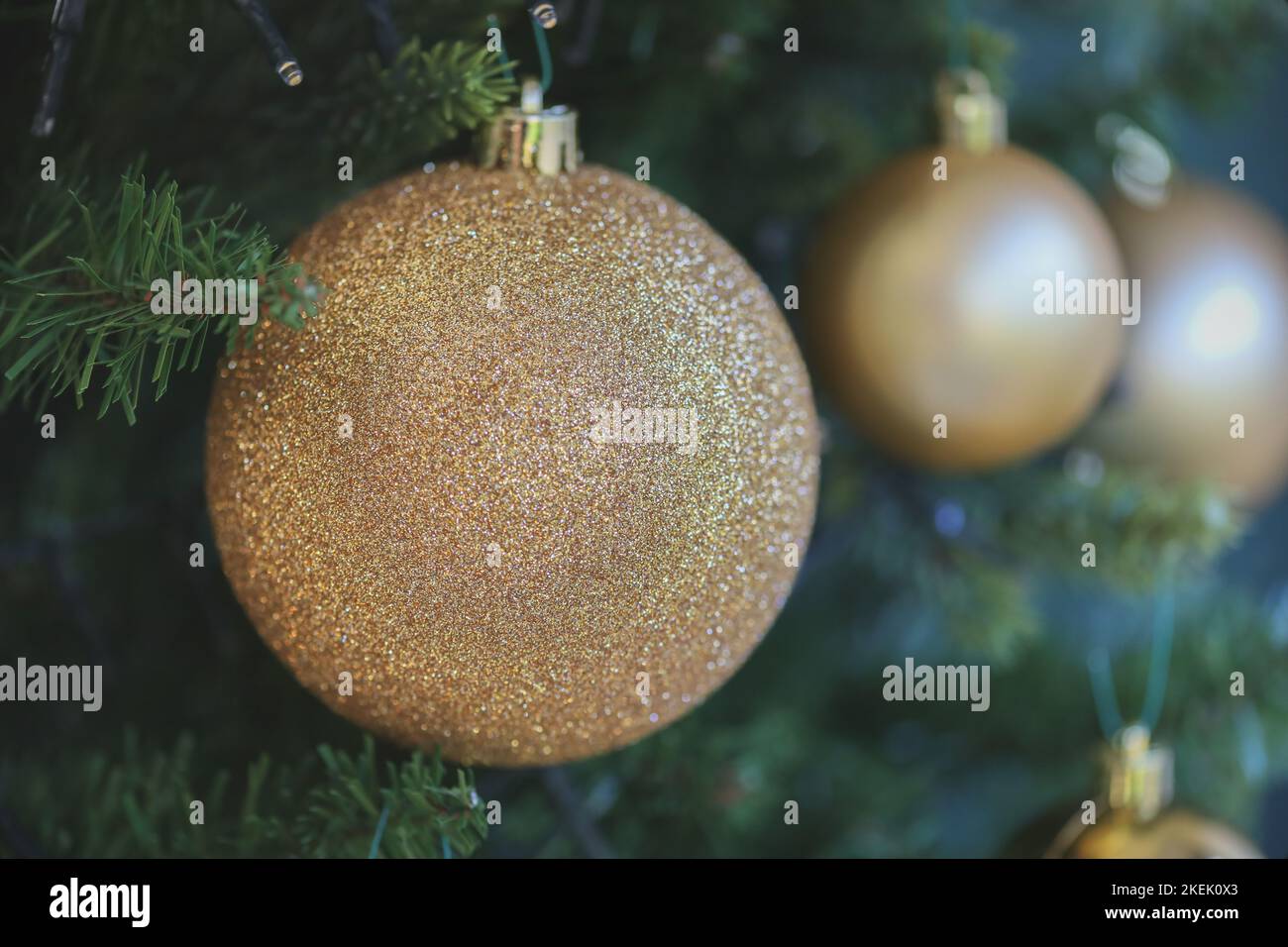 Boule dorée scintillante accrochée à un sapin de Noël / décoration de Noël Banque D'Images