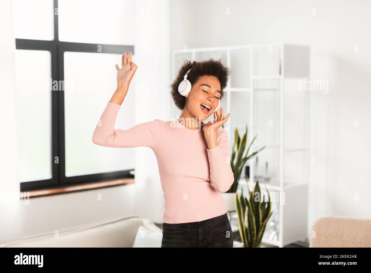 Joyeuse femme afro-américaine millénaire dans un casque sans fil chante la chanson, aime la musique préférée, danse Banque D'Images