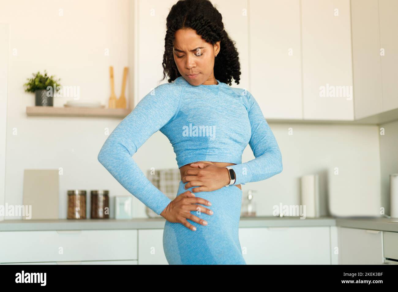 FIT afro-américaine femme ayant le dos de traumatisme, souffrant de douleur, debout dans la cuisine intérieure, l'espace de copie Banque D'Images