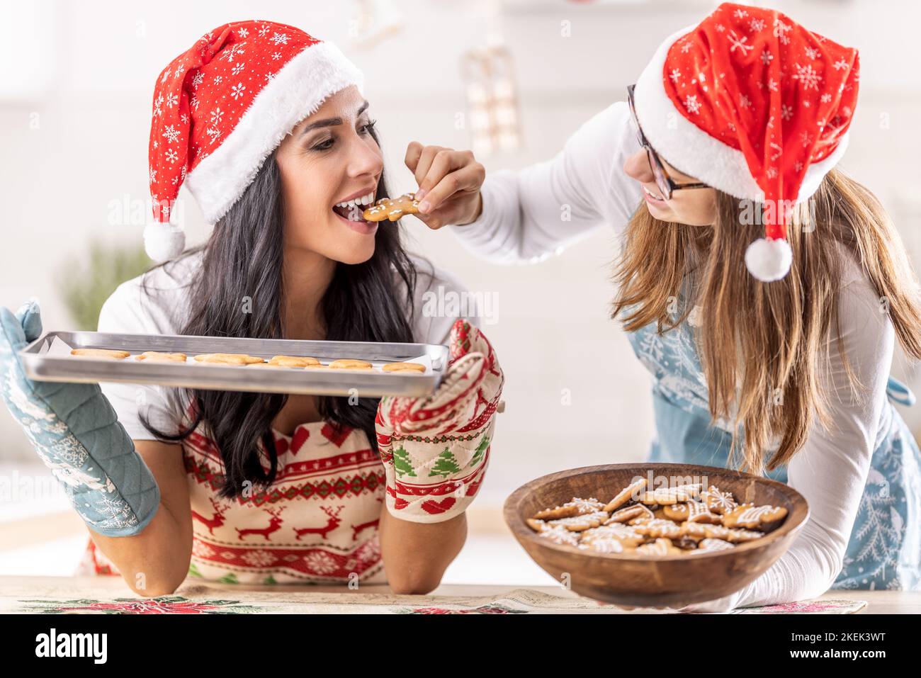 La mère et la fille goûtent du pain d'épice de Noël fraîchement cuit. Banque D'Images