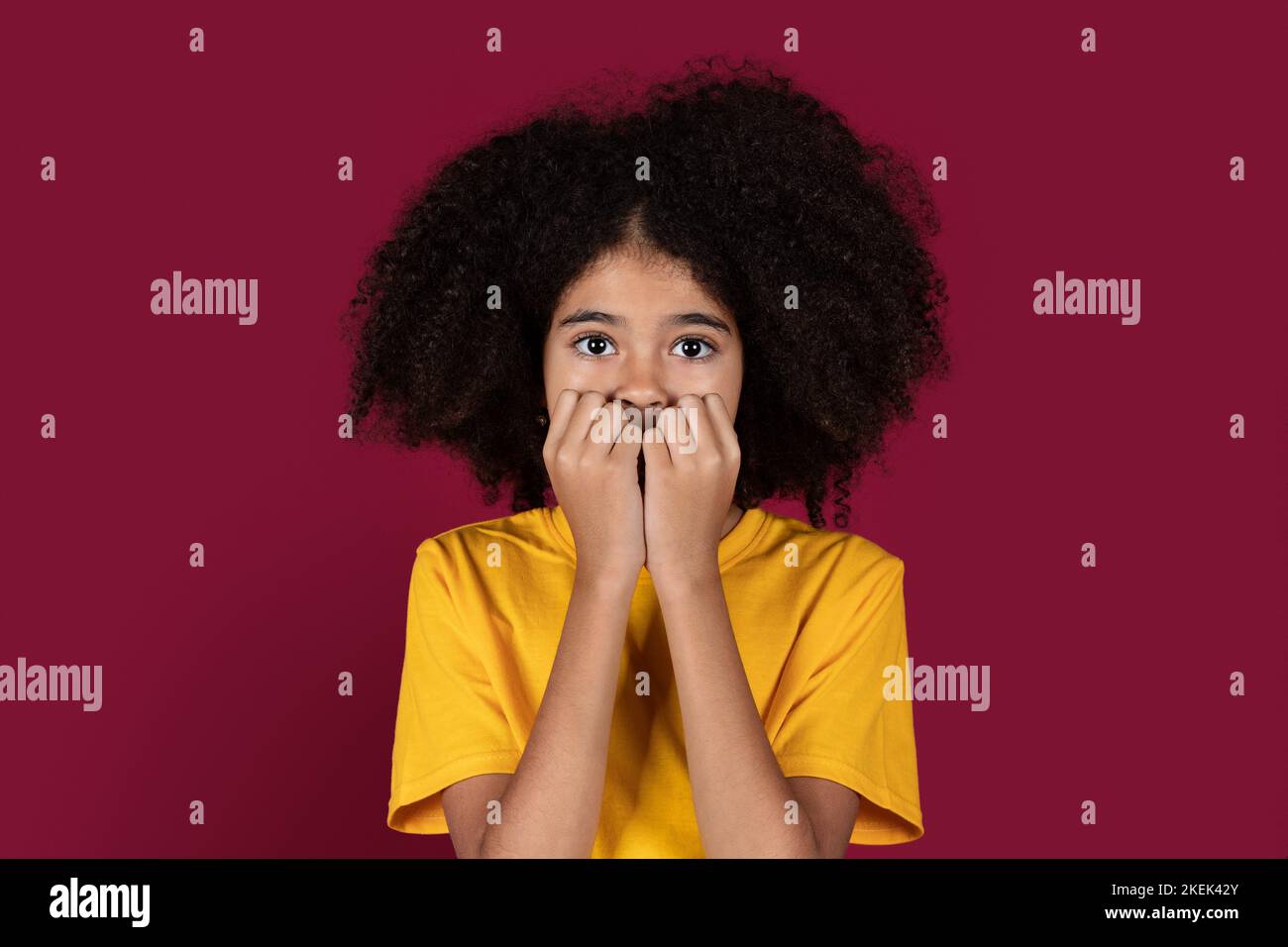 Un enfant afro-américain effrayé qui la couvre la bouche Banque D'Images