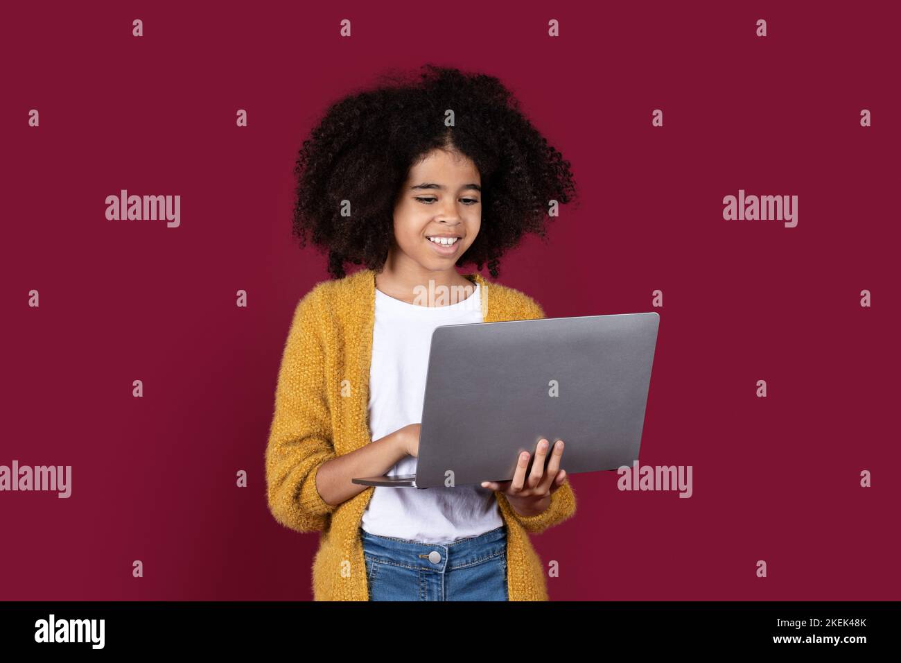 Adorable écolière noire utilisant un ordinateur moderne Banque D'Images