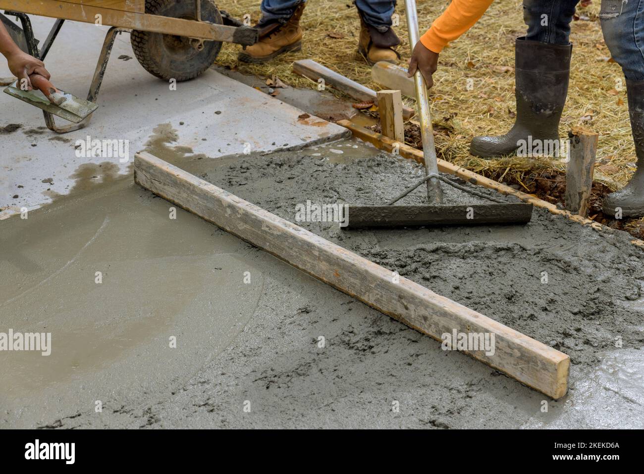 Il y a des ouvriers de la construction qui versent du ciment sur le côté de la maison afin de créer un nouveau trottoir supplémentaire Banque D'Images