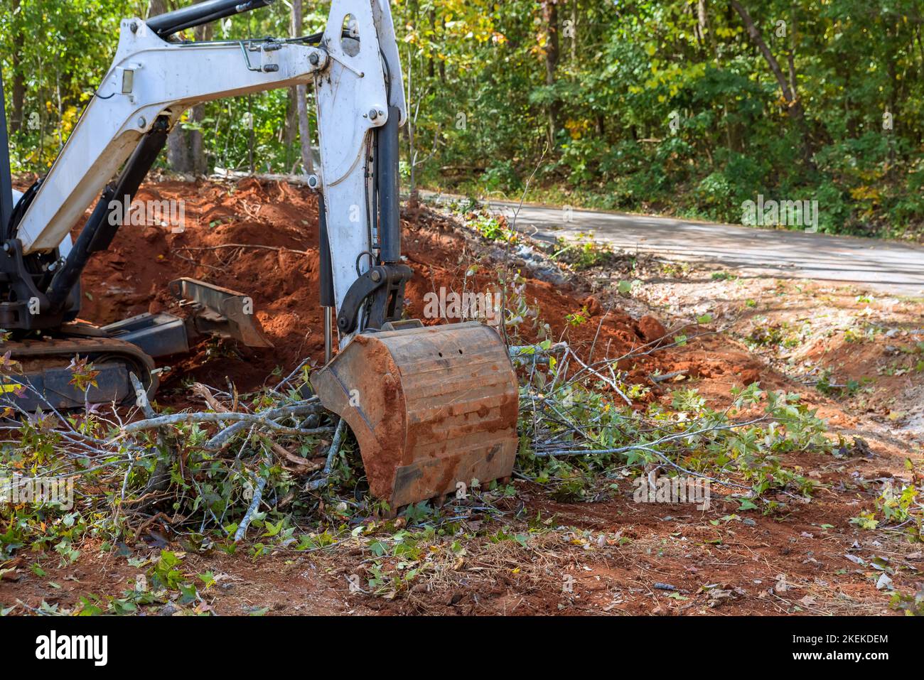 La mini-chargeuse de tracteur a été utilisée pour dégager les racines des arbres pour la construction de lotissements sur une parcelle de terrain déblayée pendant les travaux d'aménagement paysager. Banque D'Images