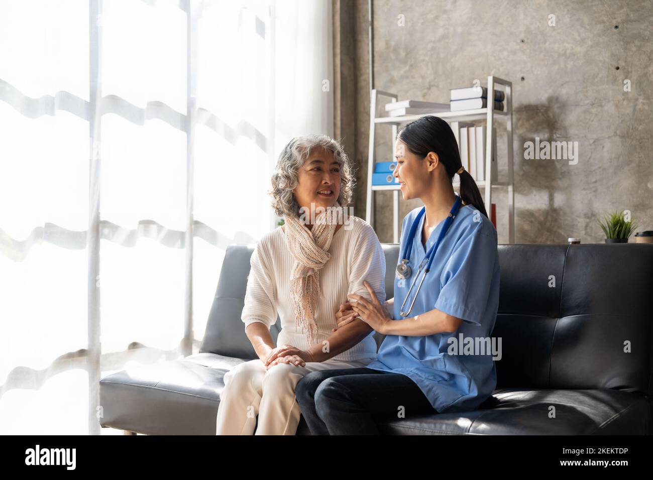 Le patient heureux tient le soignant pour une main tout en passant du temps ensemble. Femme âgée en maison de soins infirmiers et infirmière. Banque D'Images