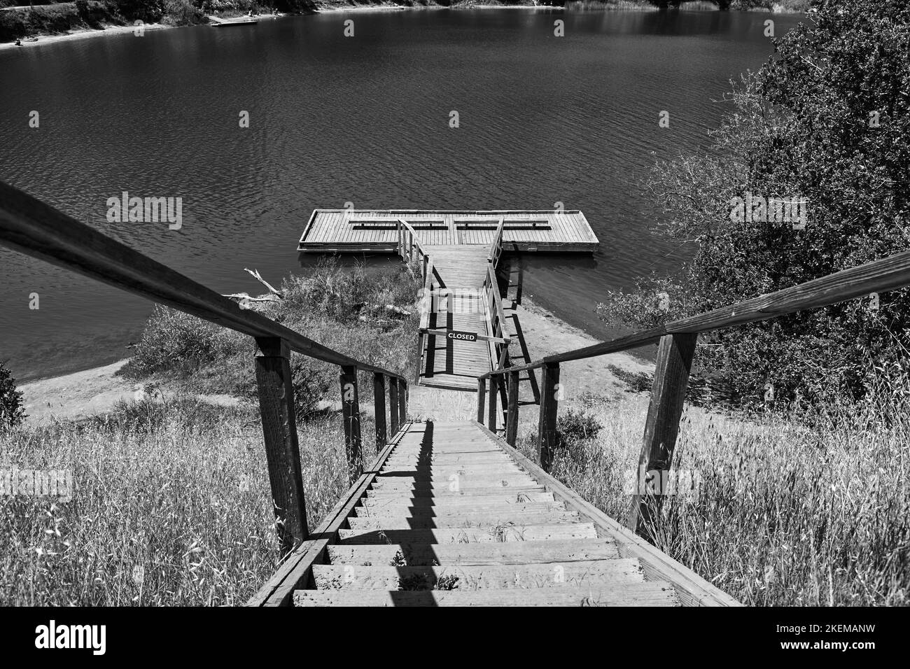 Un plan noir et blanc d'escaliers menant à un quai en bois sur la côte d'un lac Banque D'Images