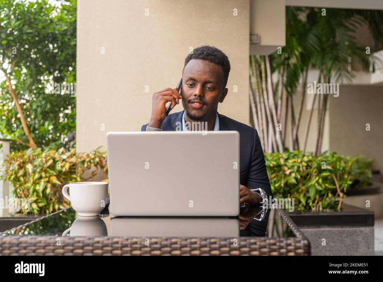 Portrait d'un beau homme d'affaires africain noir portant un costume et utilisant un ordinateur portable Banque D'Images