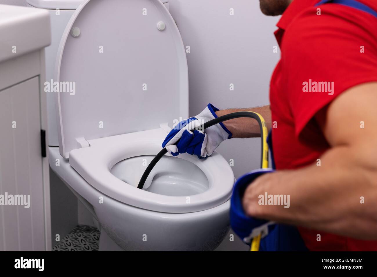 plombier débouchant les toilettes bloquées avec jet d'eau à la salle de bains de maison. service de nettoyage d'égout Banque D'Images