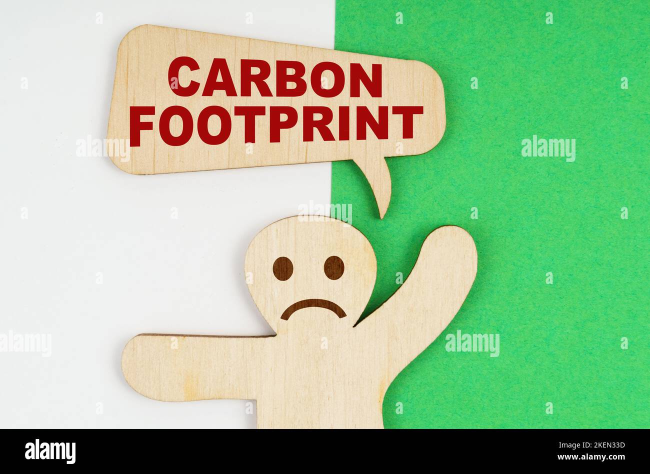 Concept environnemental. Sur un fond vert et blanc, une triste figure en bois d'un homme et une plaque avec l'inscription - empreinte carbone Banque D'Images