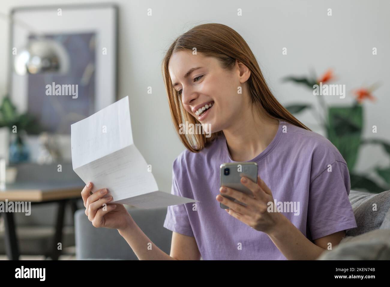 Une jeune femme heureuse utilisant une application mobile pour payer la facture, les taxes ou les assurances de son ménage utilise des services bancaires Internet sécurisés Banque D'Images