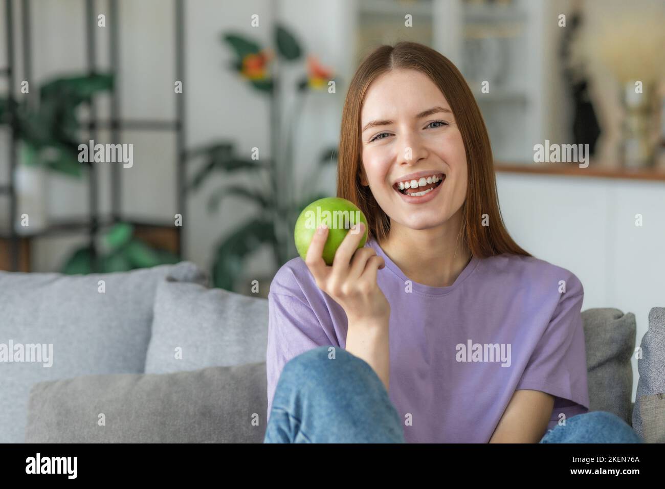 Un mode de vie sain. Bonne belle jeune femme caucasienne avec des dents blanches sourit largement et tenant la pomme verte fraîche Banque D'Images