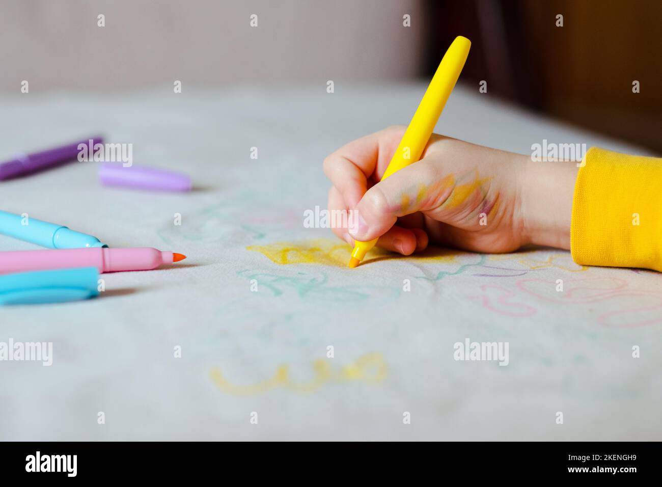 Le dessin à la main de l'enfant avec un stylo feutre rose sur la sellerie grise du canapé. La vie quotidienne taches sales pour le lavage et le concept propre Banque D'Images