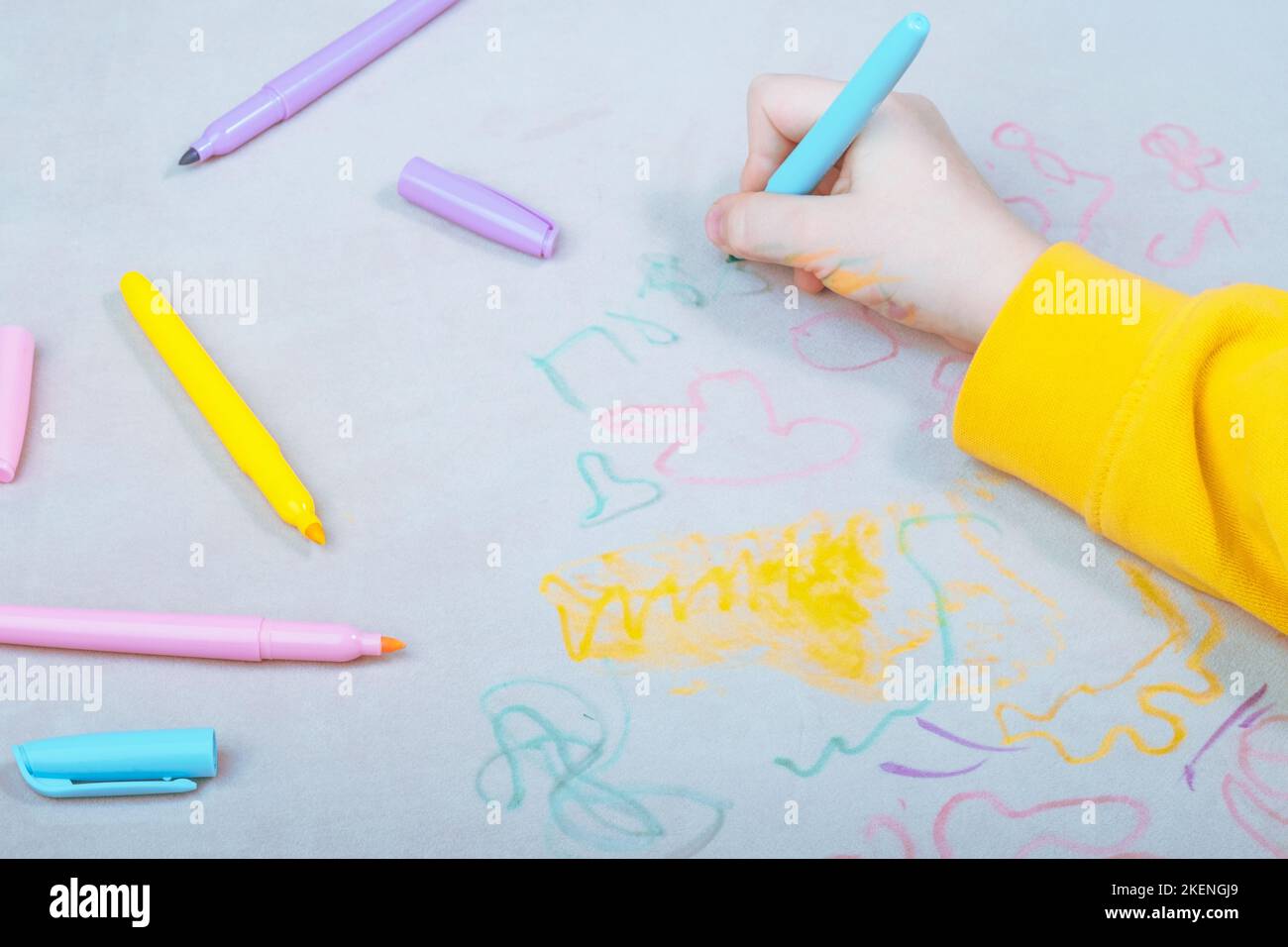 La main de l'enfant dessin avec un stylo feutre sur la sellerie du canapé. Vue du dessus. Tissus de mobilier. Concept de nettoyage Banque D'Images