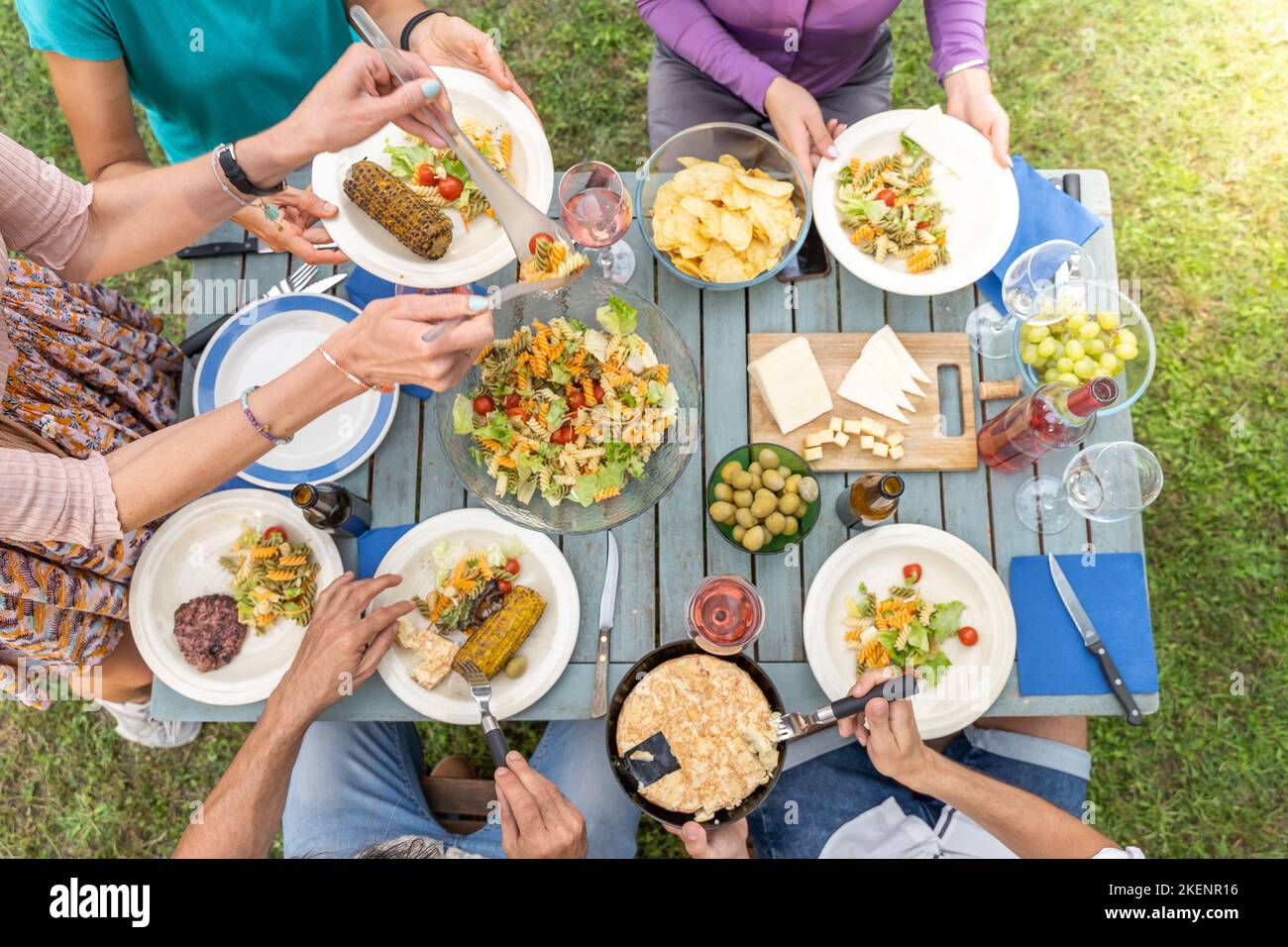 Vue de dessus de la famille assis à une table en bois pour dîner. Ils ont des assiettes pleines de nourriture et des verres avec des boissons. Banque D'Images