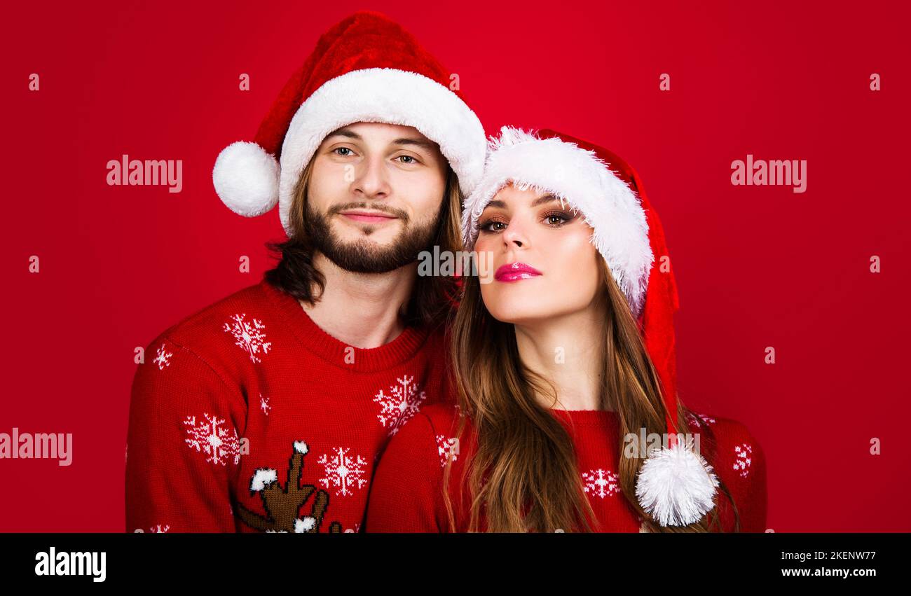 Jeune couple en chandails de Noël et chapeaux de père Noël. Bonne fête du nouvel an. Joyeux vacances. Banque D'Images
