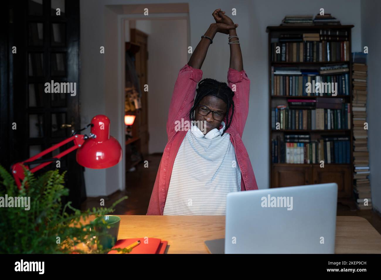 Fatigué endormi Afro-américain homme indépendant tire les bras vers le haut pour s'étirer après la journée de travail difficile Banque D'Images