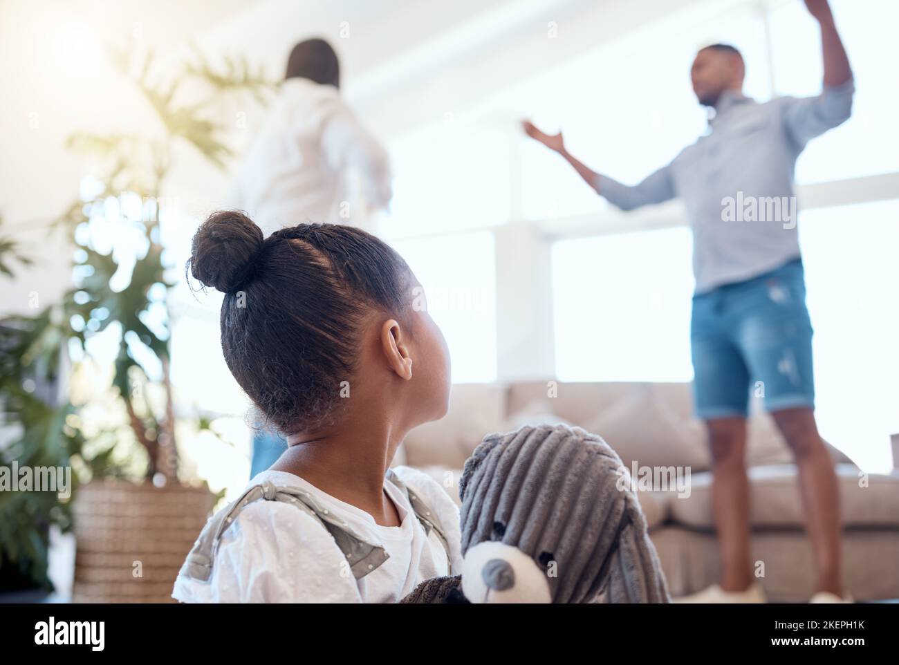 Argument, divorce et peur enfant dans le salon avec un ours en peluche pour le confort dans une maison moderne. La famille, la rupture et les parents se battent avec Banque D'Images