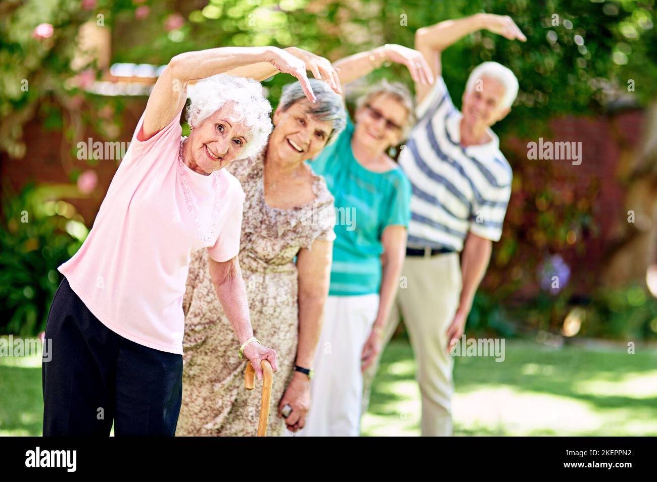 N'étaient pas jeunes mais nous vivons comme ça. Un groupe de personnes âgées souriantes s'exerçant à l'extérieur. Banque D'Images