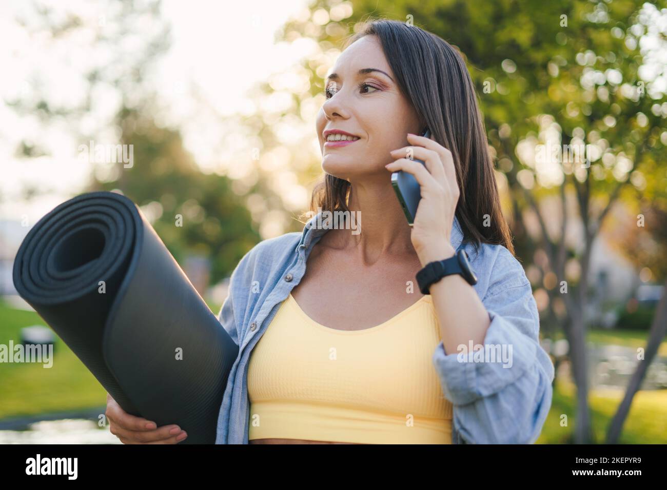 Portrait d'une femme sportive en pause après l'entraînement, en marchant dans le parc et en utilisant un téléphone portable pour parler à quelqu'un. Sport, passe-temps, concept de technologie Banque D'Images