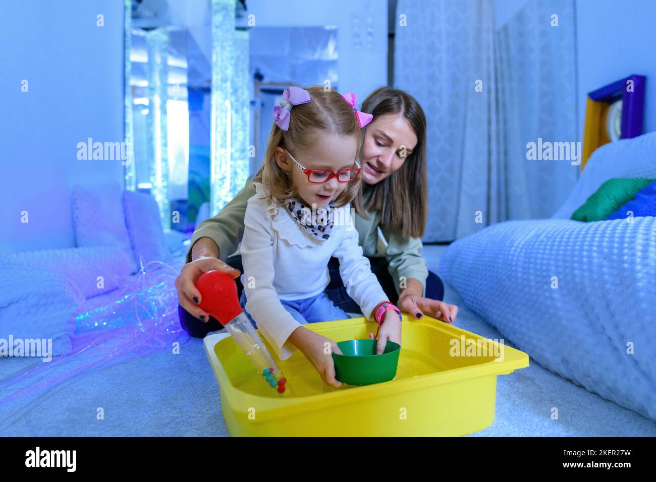 Enfant avec un handicap physique dans la chambre stimulante sensorielle, snoezelen. Enfant vivant avec une paralysie cérébrale interagissant avec son thérapeute pendant la thérapie Banque D'Images