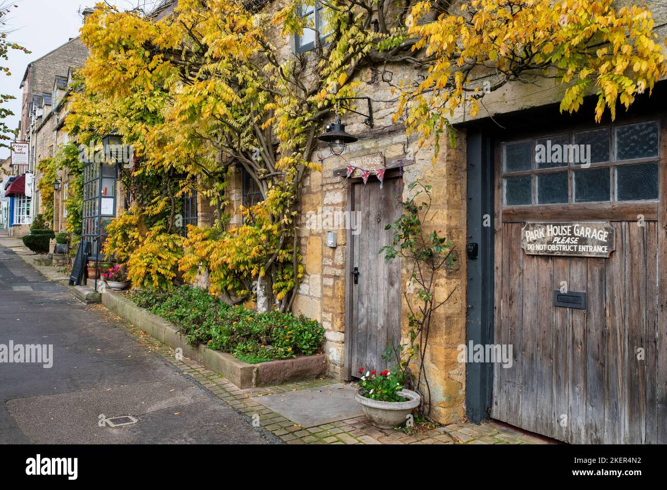 Feuillage de wisteria d'automne le long de la rue du parc. Stow on the Wold, Gloucestershire, Cotswolds, Angleterre Banque D'Images