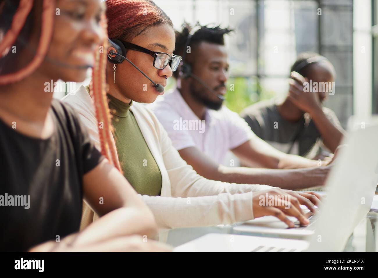 Belle femme afro-américaine souriante travaillant dans un centre d'appels avec une équipe diversifiée Banque D'Images